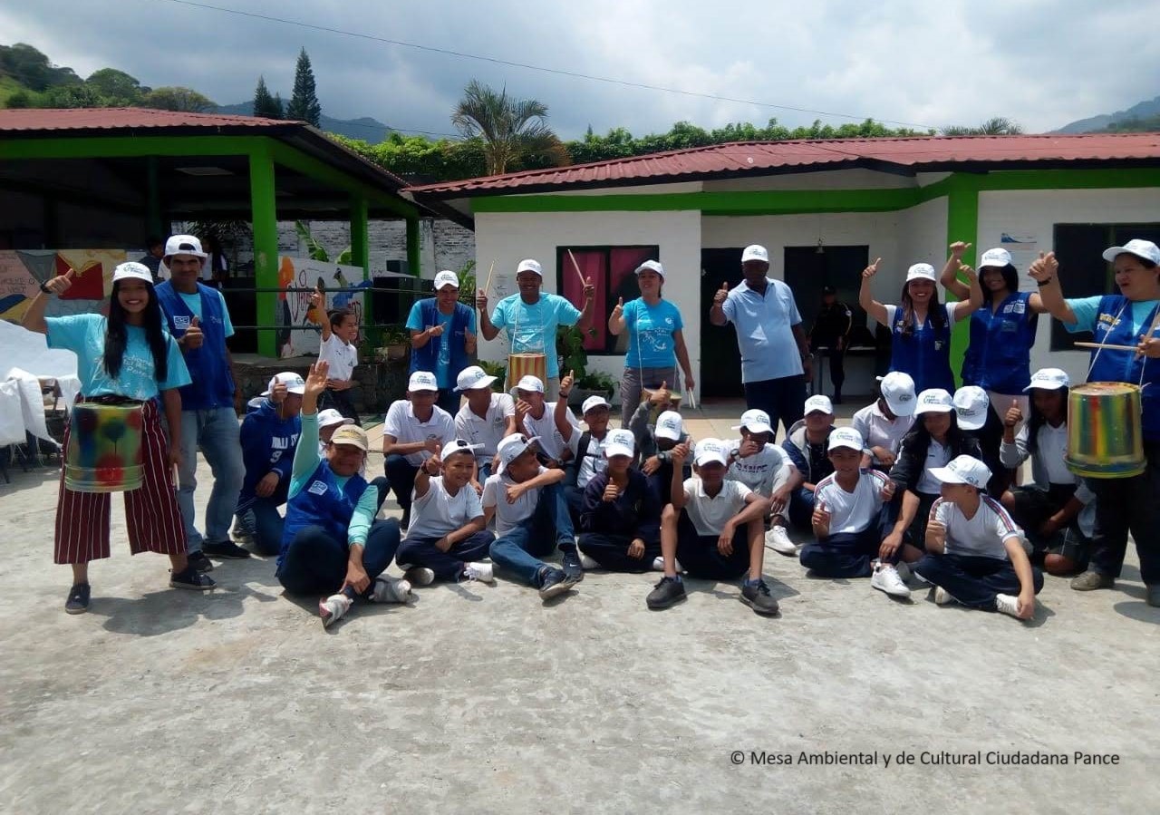 Grupo de personas sentadas posando para una foto con gorras de color blanco