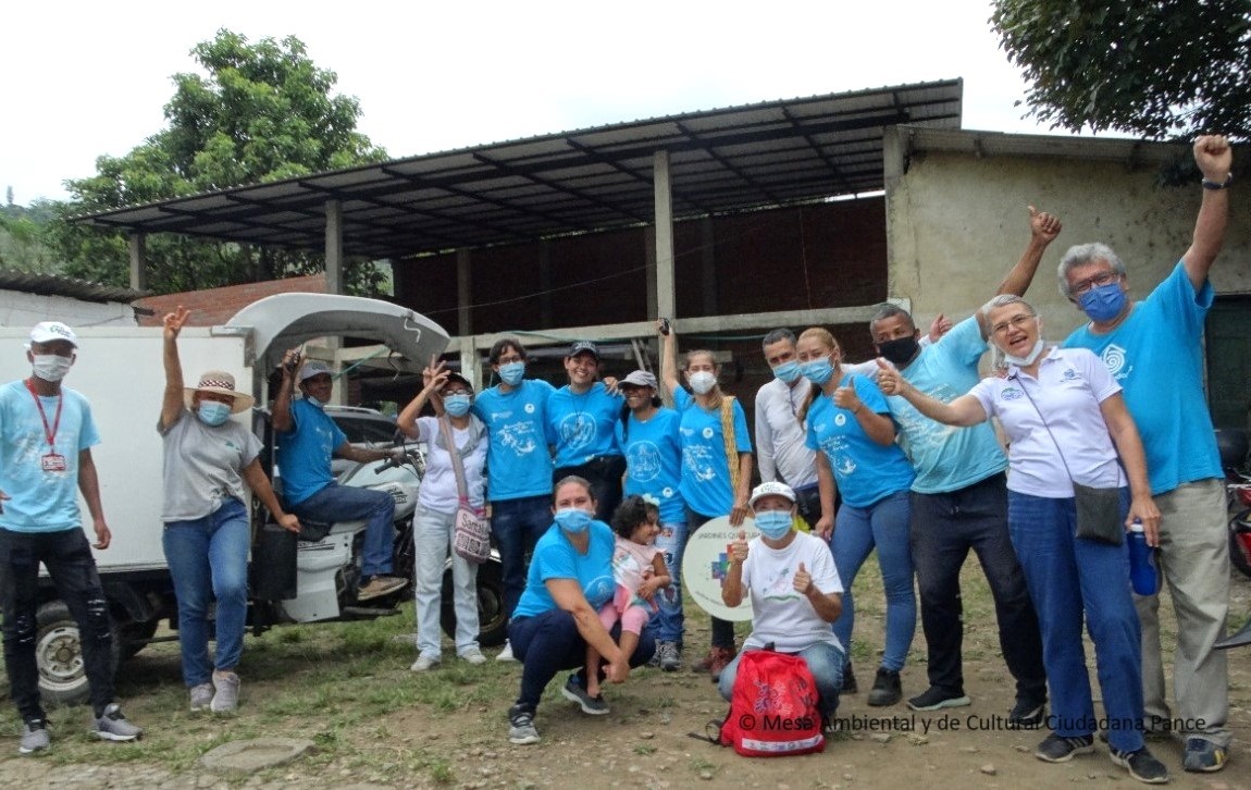 Grupo de personas de pie con los brazos abiertazulos vistiendo camisas de color 